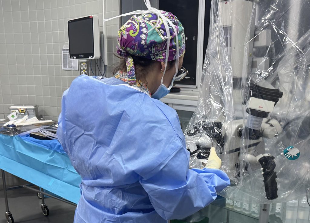 Enfermera instrumentista preparando el microscopio quirúrgico antes de una intervención de neurocirugía
