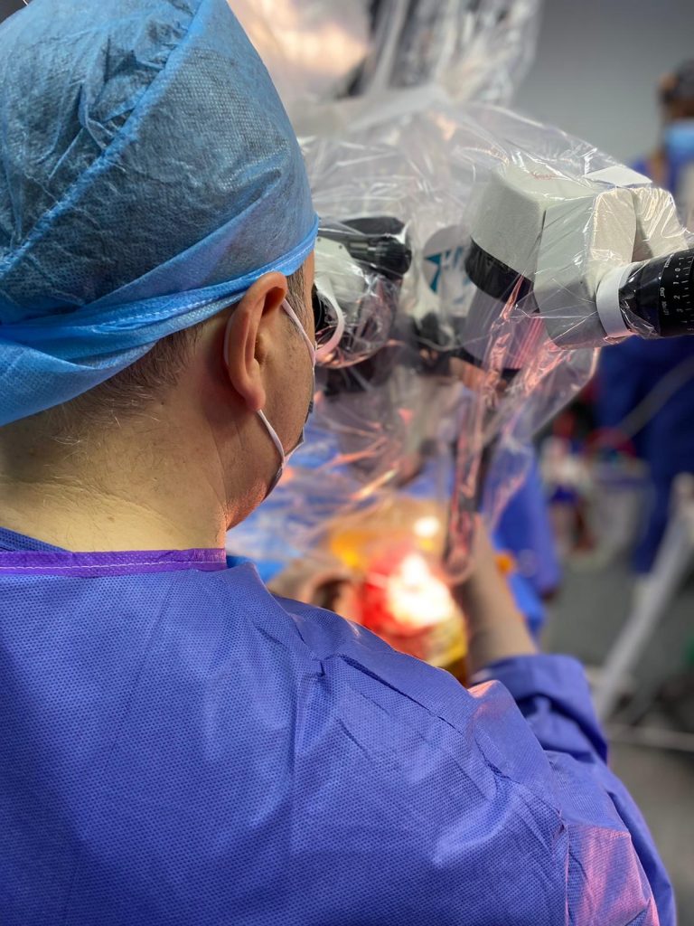 Neurocirujano utilizando microscopio quirúrgico durante una intervención neuroquirúrgica