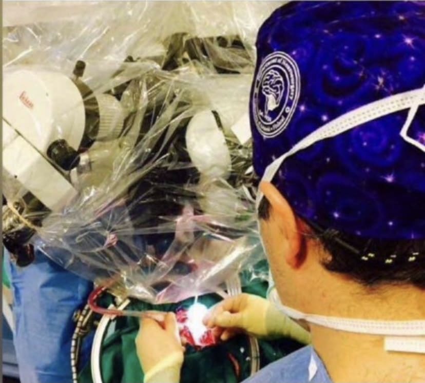 Neurocirujano (Dr. Antonio López) realizando cirugía cerebral con microscopio quirúrgico